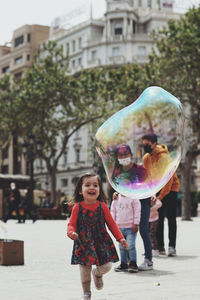 Full length of woman with bubbles in city