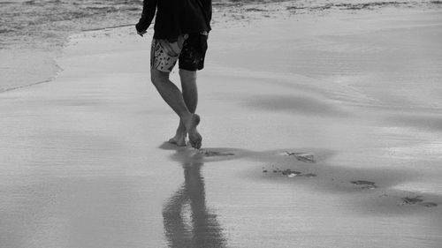 Low section of man walking on beach