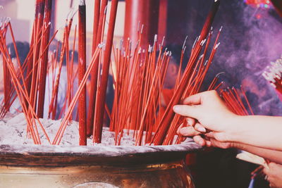 Low angle view of hand holding candle against building