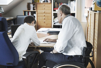 Disabled man assisting son in studying at home