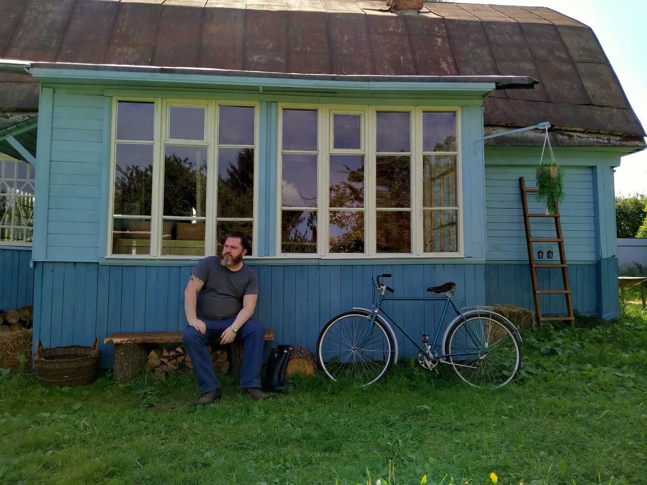 MAN SITTING ON BICYCLE AGAINST BUILDING