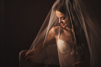 Smiling bride under veil in studio