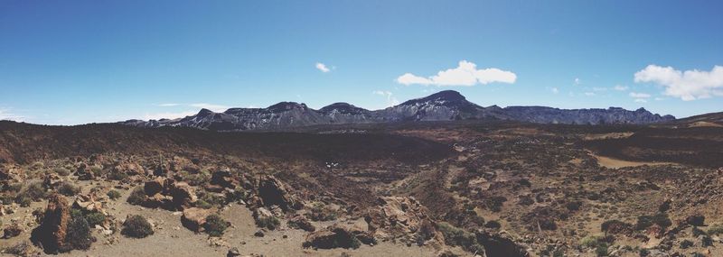 Panoramic view of landscape and mountains against blue sky on sunny day