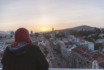 Rear view of man looking at cityscape against sky