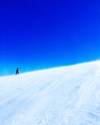 Person skiing on snowcapped mountain against blue sky