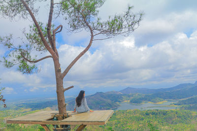 Rear view of people sitting on landscape against sky