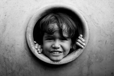 Close-up portrait of cute boy looking through circle at playground