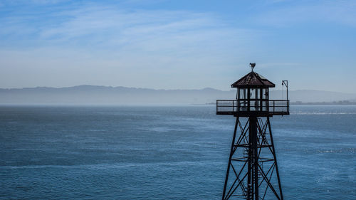 Lighthouse by sea against sky