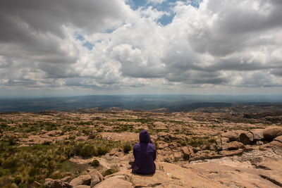 Rear view of woman looking at rock against sky