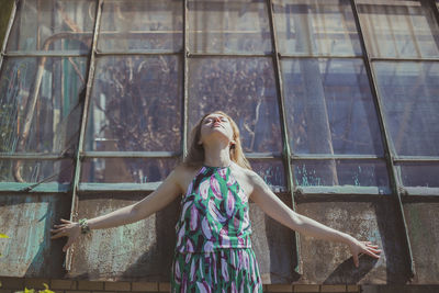 Young woman with closed eyes posing against tall windows scenic photography