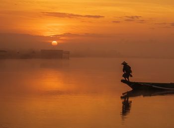 Silhouette woman against sea during sunset