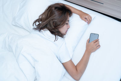 Young woman using mobile phone on bed