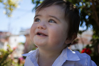 Close-up of thoughtful cute baby boy smiling outdoors