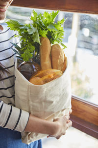 Midsection of woman holding groceries in bag