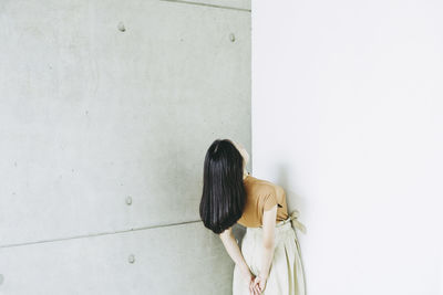 Rear view of person standing against white wall