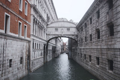 Bridge over canal amidst buildings against clear sky