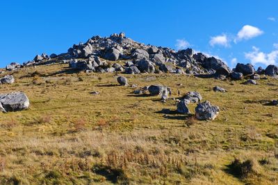 Panoramic view of rocks on field against blue sky