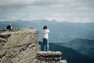 Rear view of man looking at mountain range against sky