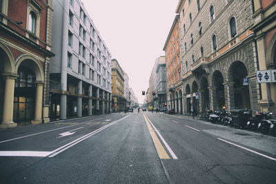 Road amidst buildings in city against clear sky