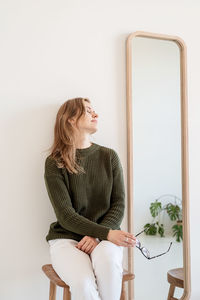 Minimal light and airy interior design. attractive young woman in white jeans and green sweater 