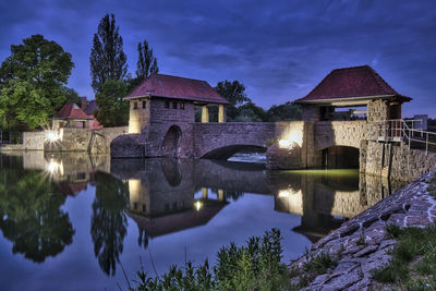 Building by lake against sky at dusk