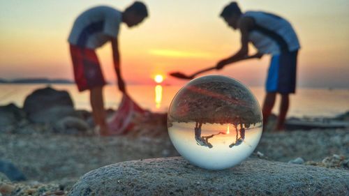 Close-up of ball on beach against sky during sunset