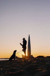 Rear view of silhouette man standing against clear sky during sunset