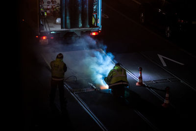 Rear view of people standing on street at night