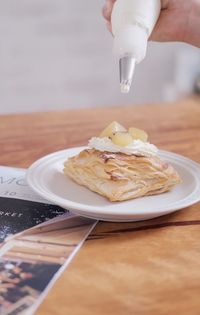 Close-up of hand holding ice cream cone on table