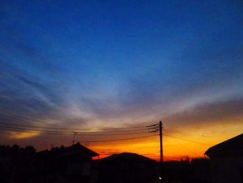 Silhouette electricity pylons against sky during sunset