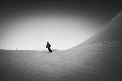 Man walking on snow covered mountain against clear sky