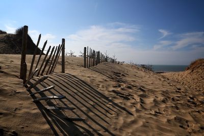 Wooden posts on beach against sky