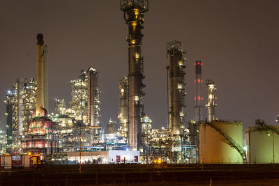 Low angle view of illuminated factory against sky at night