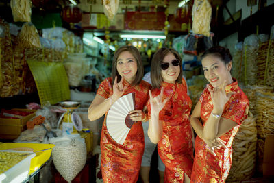 Portrait of smiling women in traditional clothing gesturing at store