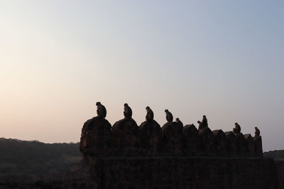 Silhouette people looking at sunset