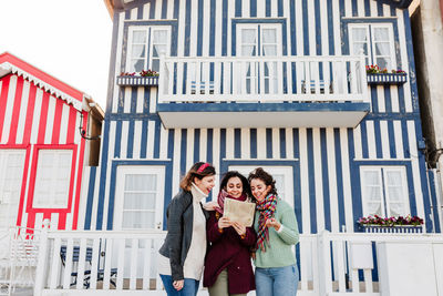 Tourist female friends reading a map in in front of colorful houses.costa nova, aveiro, portugal