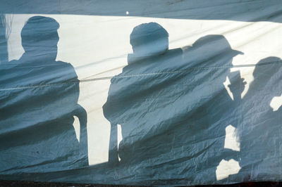 Shadows of friends on tarpaulin outdoors