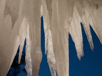 Close-up of frozen ice from roof with blue sky background 