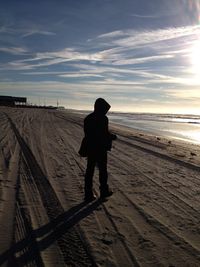 Silhouette man standing on beach against sky during sunset