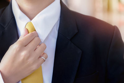 Close-up midsection of businessman adjusting necktie