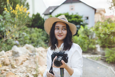 Young asian woman in a park holding camera, outdoor portrait. summer portrait. work and hobbies 