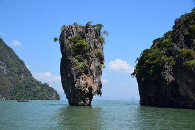 Rock formation by sea against blue sky