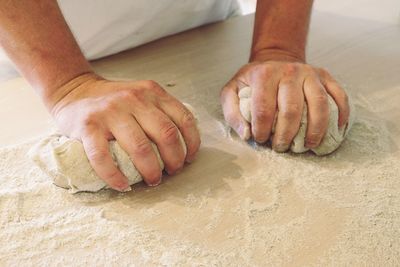 Cropped image of person kneading dough on table