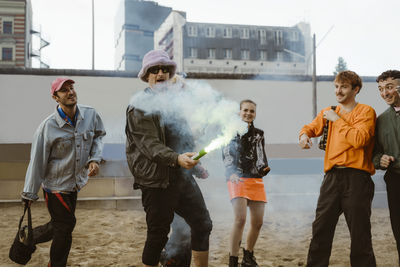 Gay man holding distress flare with non-binary friends at park