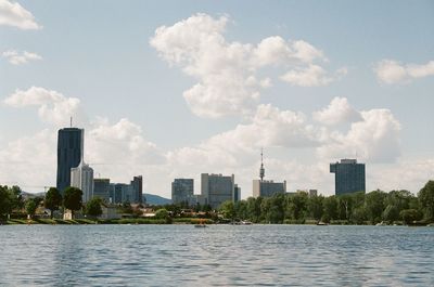 Buildings by river against sky in city