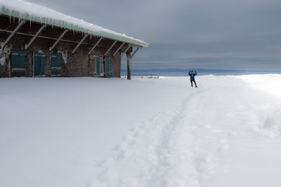 Person standing on snow at ski resort against cloudy sky