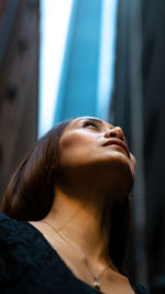 Low angle view of thoughtful woman standing in city