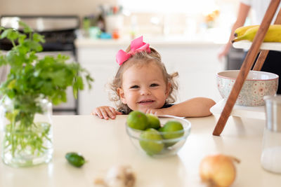 Portrait of cute girl with vegetables on table at home