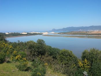 Scenic view of lake against clear blue sky