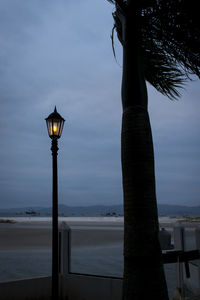 Street light by sea against sky at dusk